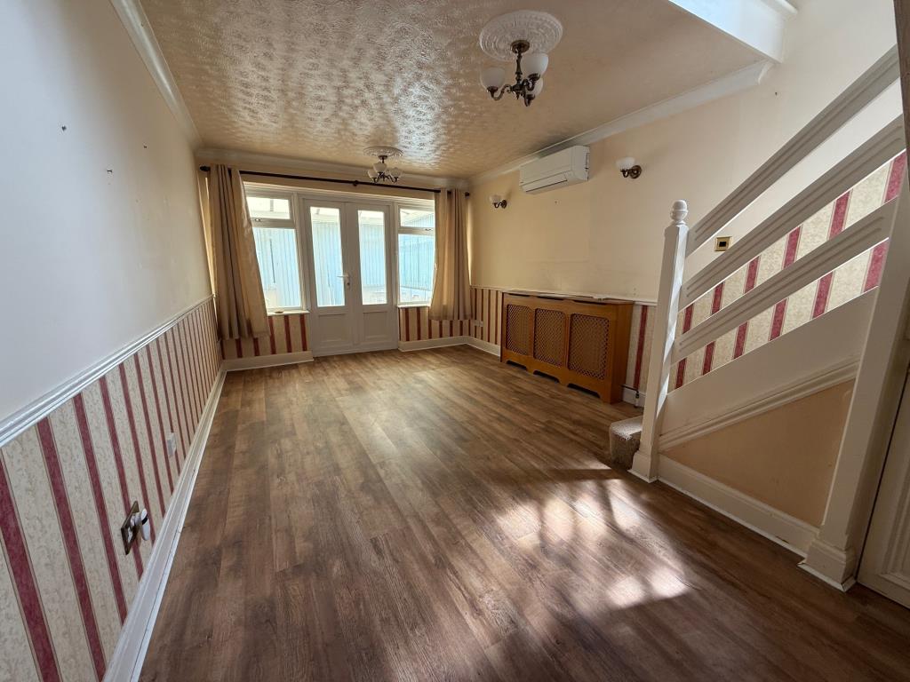 Lot: 111 - END-TERRACE ONE-BEDROOM HOUSE - Living area with wall mounted air conditioning unit and stairs to first floor